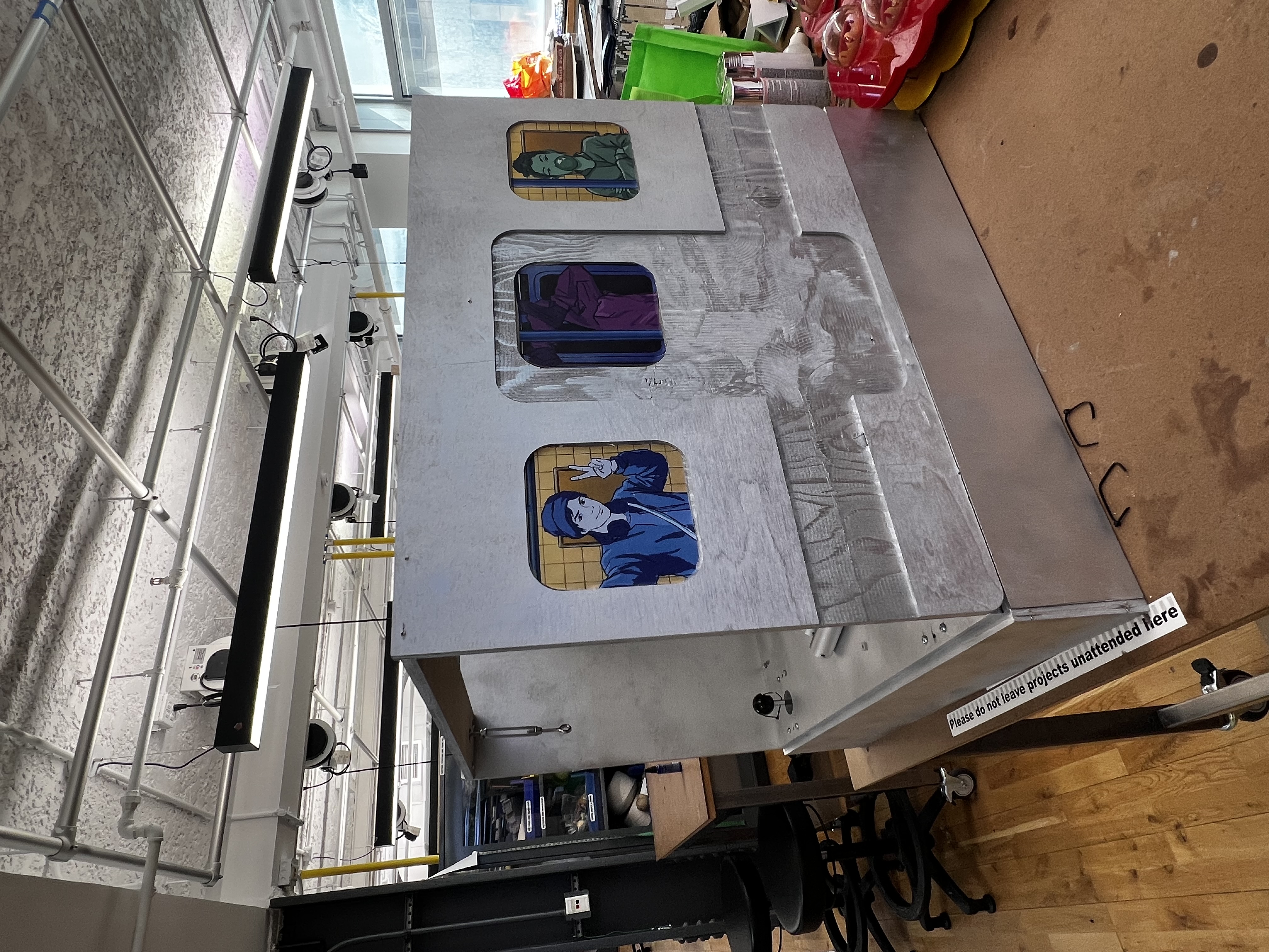 The chrome silver arcade cabinet in the workshop with vinyl character stickers on the sides