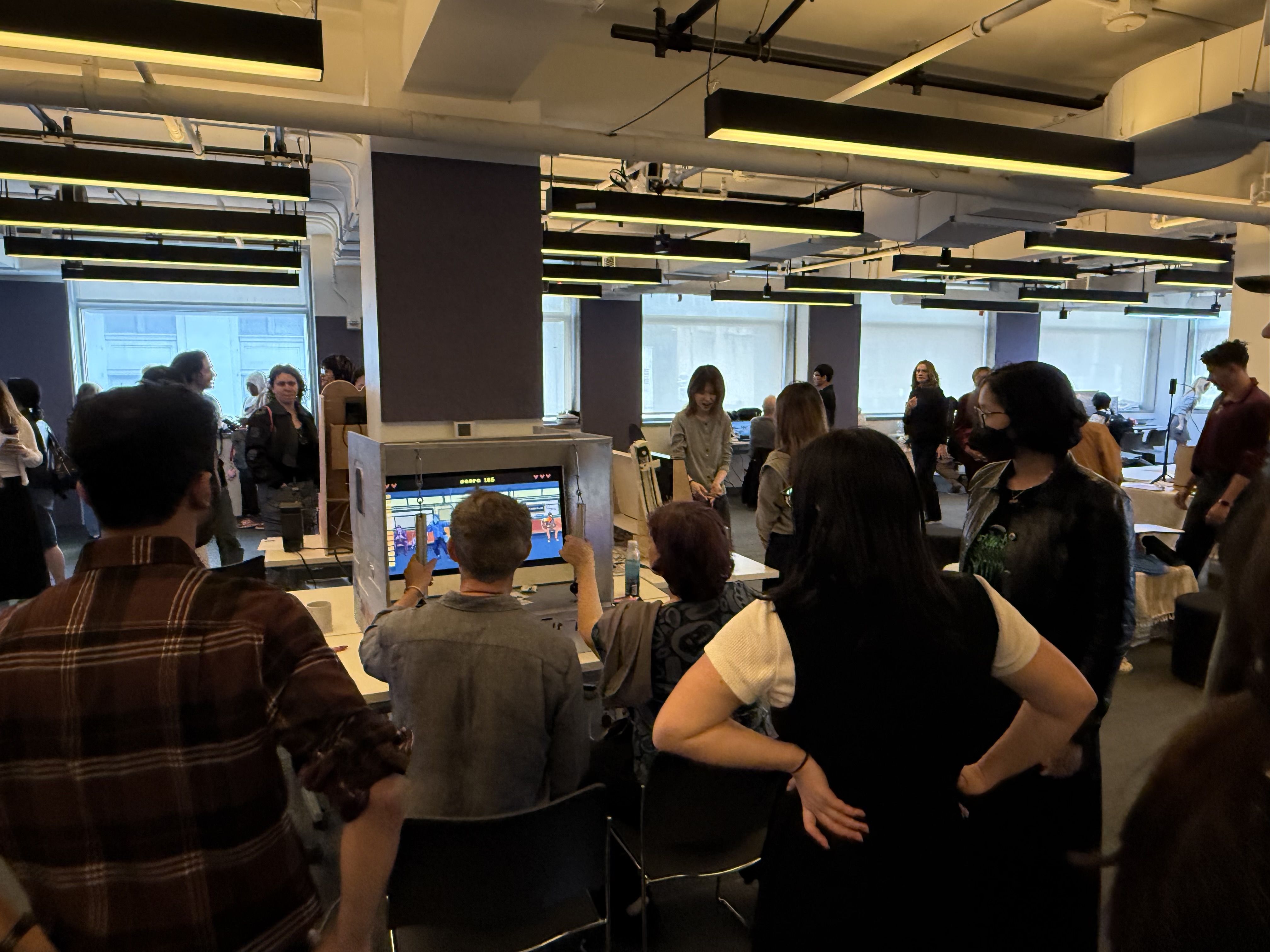 Large crowd gathered around the Hold On New York arcade cabinet at the ITP Spring Show